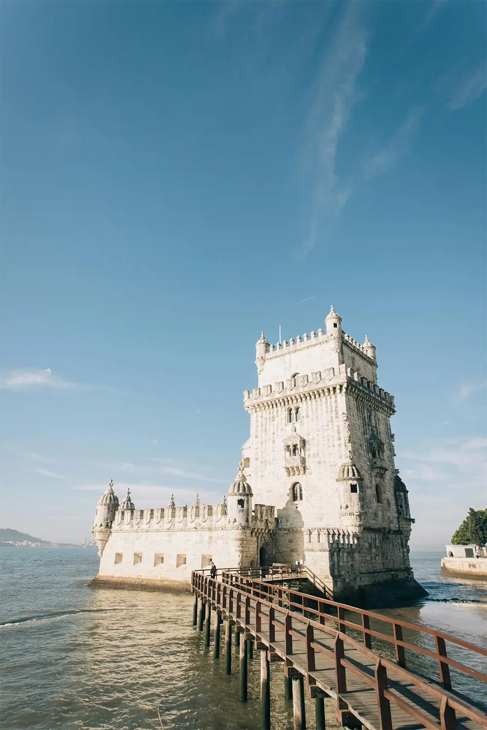 Belem Tower in Lisbon, Portugal, under a clear sky with a scenic walkway.