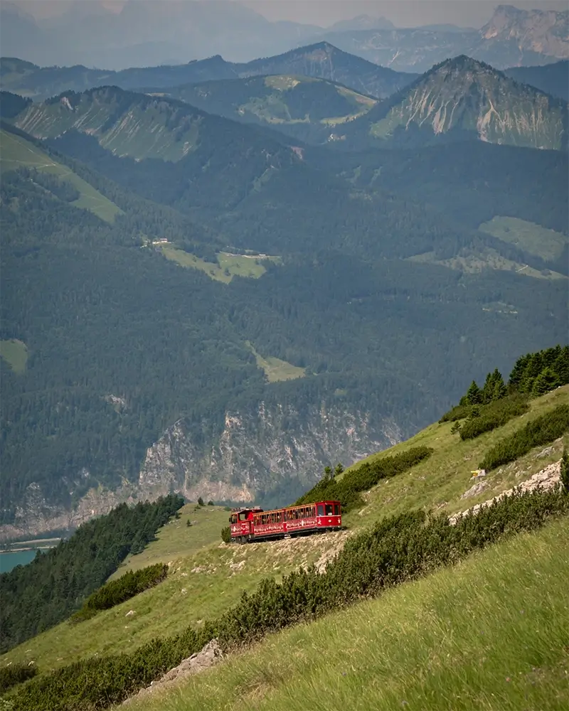 Panoramic view of turquoise Lake Wolfgang and Austrian Alps from left side of ascending Schafberg railway train